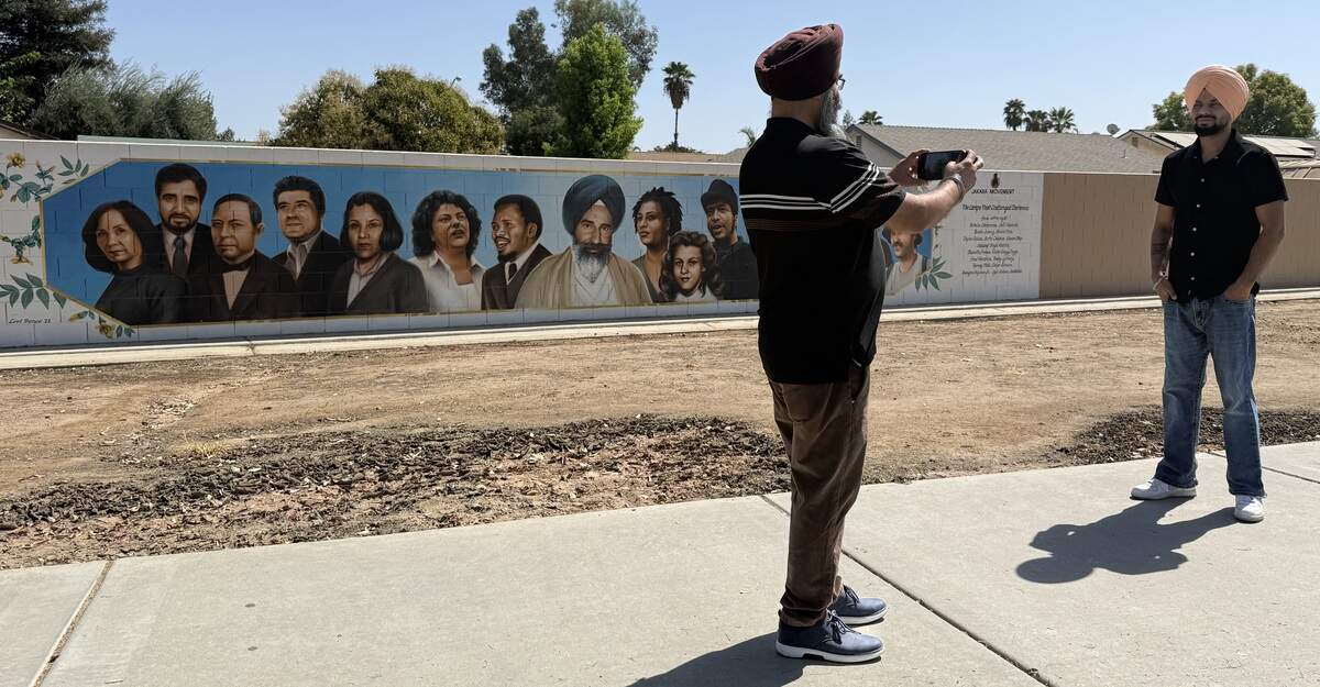 A Sikh man photographs his associate in front of murals depicting Jaswant Singh Khalra and other human rights activists in Fresno.